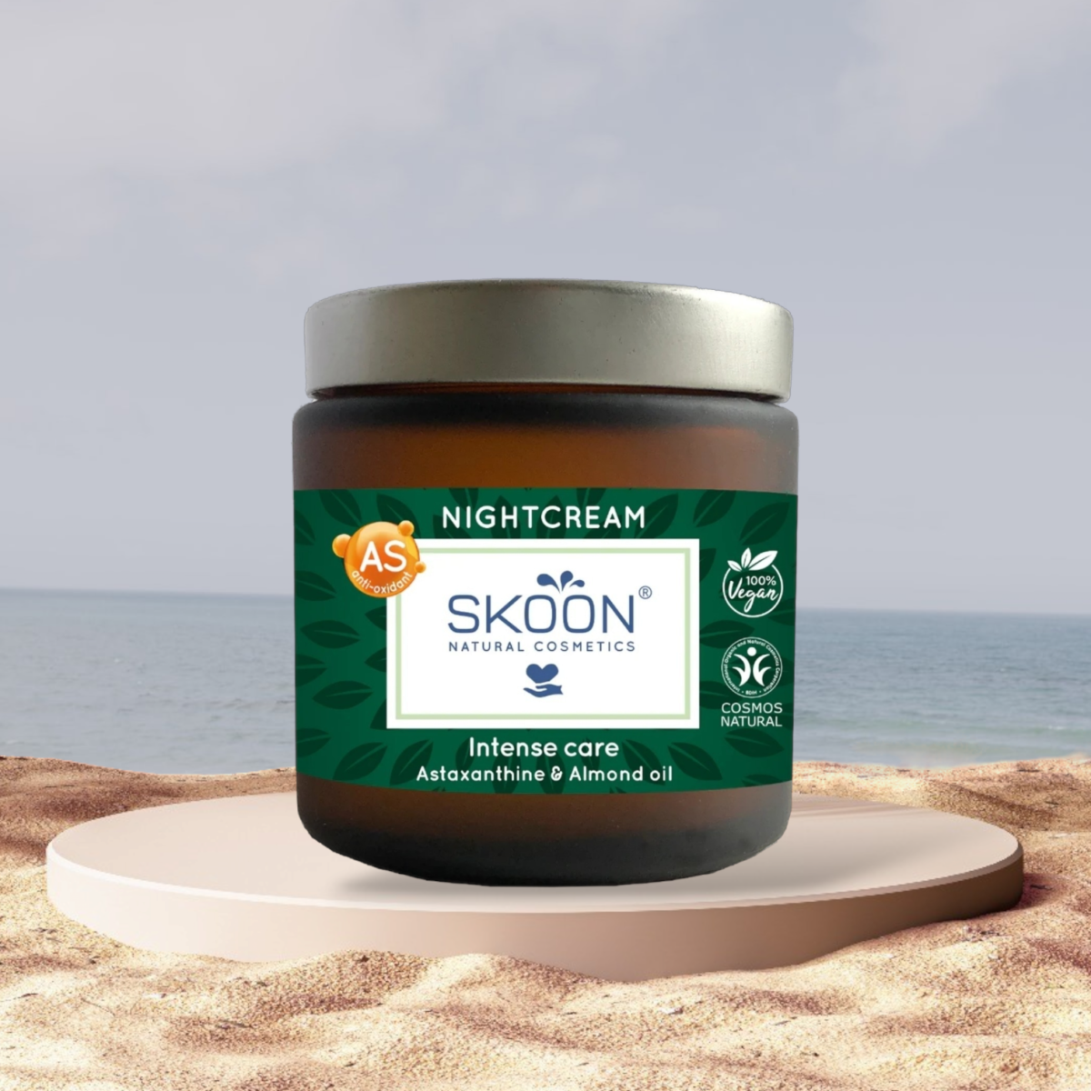 Pureday En krukke Økologisk natcreme - Skoon med astaxanthin og mandelolie, udstillet på en piedestal mod en naturskøn strandkulisse.