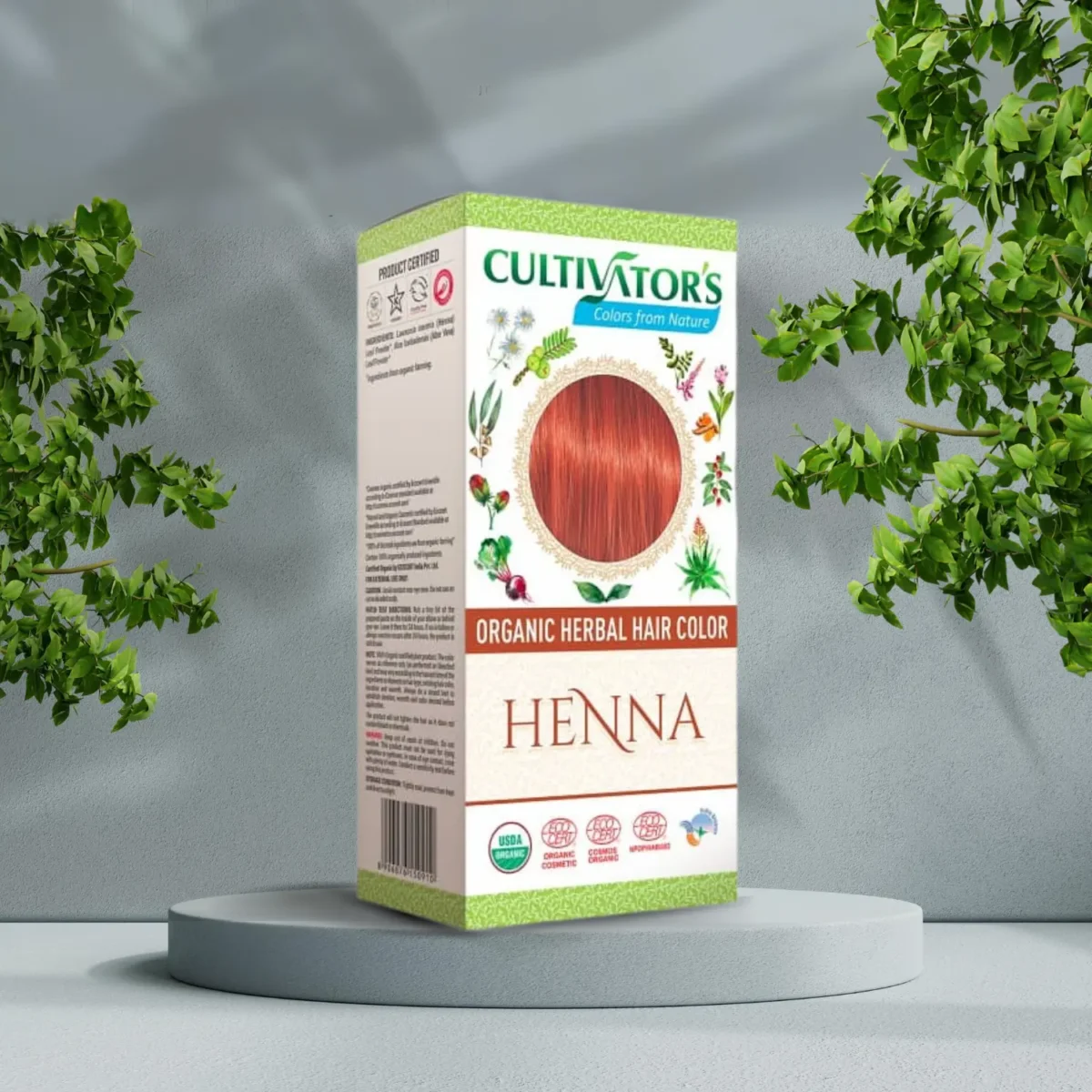 Pureday En æske Cultivators Henna 100g økologisk urte-hårfarve, vist på en piedestal omgivet af naturligt frodige grønne planter, mod en grå baggrund.